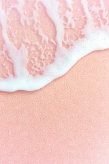 Fototapeta premium Soft pink sand beach with gentle white sea foam creating serene and calming coastal scene
