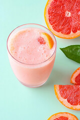 Refreshing grapefruit smoothie in glass with fresh grapefruit slices on pastel background. Vibrant and healthy
