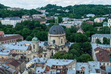 From above the Dominican Church in Lviv Ukraine stands out with its distinctive dome surrounded by the old city's buildings and trees offering a picturesque overview of the historical significance.