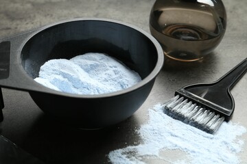 Bleaching powder and hairdresser's tools on grey table, closeup