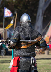 Knight in armor at Medieval Fair in South Australia, surrounded by tents, flags, and participant of the local community event