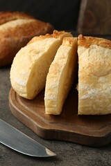 Different types of fresh bread and knife on dark textured table, closeup
