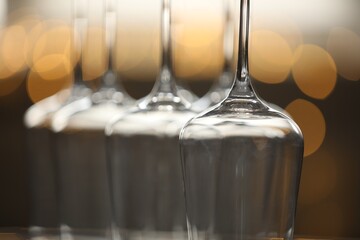 Upturned empty clean glasses on blurred background, closeup. Bokeh effect