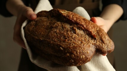 Woman with fresh loaf of bread on grey background, closeup