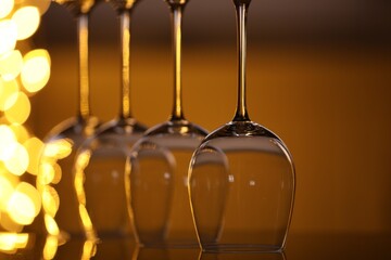 Many clean glasses on glass mirror surface against blurred lights, closeup. Bokeh effect