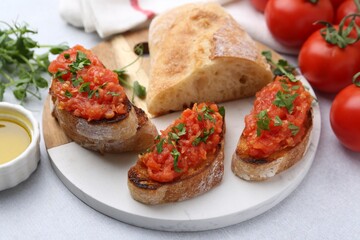 Tasty bread with tomatoes, parsley and oil on light table, closeup