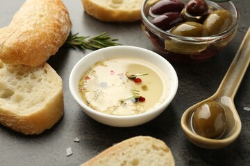 Sliced bread with oil, olives and spices on black table, closeup