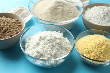 Different types of flour on light blue background, closeup