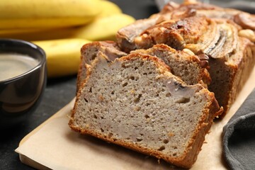 Cut banana bread with nuts and coffee on black table, closeup