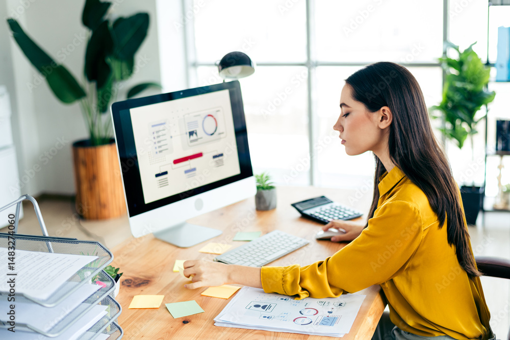 Poster professional woman working in a modern office setting, analyzing data charts on a desktop computer w