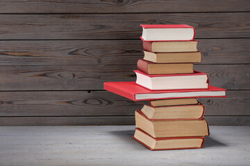 Stack of old books on grey wooden table, space for text