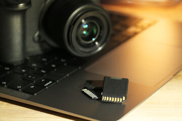 SD memory cards, laptop and photo camera on wooden table, closeup