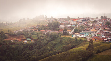 Panoramic view of Filandia, Quindío, Quindio, Colombia on a misty morning. Rural houses and winding streets fade into the fog, evoking a sense of mystery and peaceful isolation.