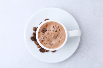 Aromatic coffee in cup, beans and saucer on light table, top view