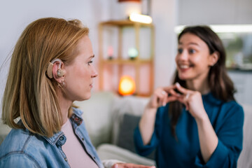 Two Girls Communicating in Sign Language, One Wearing a Hearing Aid