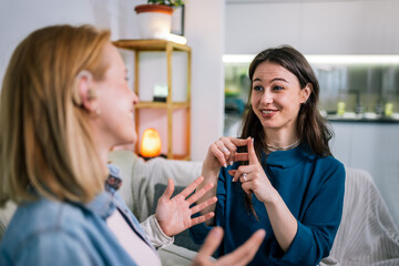 Two Girls Communicating in Sign Language, One Wearing a Hearing Aid