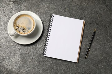 Notebook, pen and coffee on grey table, flat lay