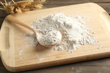 Pile of flour, spoon and spikes on wooden table, closeup