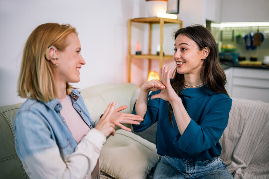 Two Girls Communicating in Sign Language, One Wearing a Hearing Aid