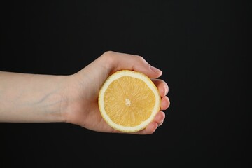 Woman with lemon on black background, closeup