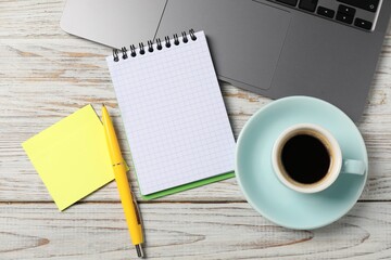 Notebook with pen, sticky note, laptop and coffee on white wooden table, flat lay