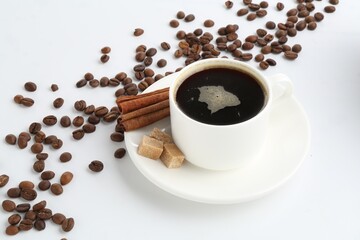 Aromatic coffee in cup, beans, cinnamon and sugar cubes isolated on white