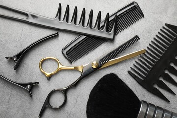 Different hairdresser's tools on grey table, flat lay