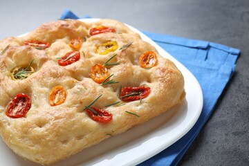 Delicious focaccia with tomatoes and rosemary on table, closeup