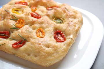 Delicious focaccia with tomatoes and rosemary on table, closeup
