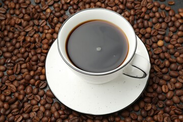 Aromatic coffee in cup on beans, above view
