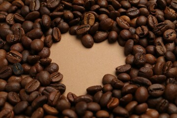Heart shaped of coffee beans on beige background, closeup