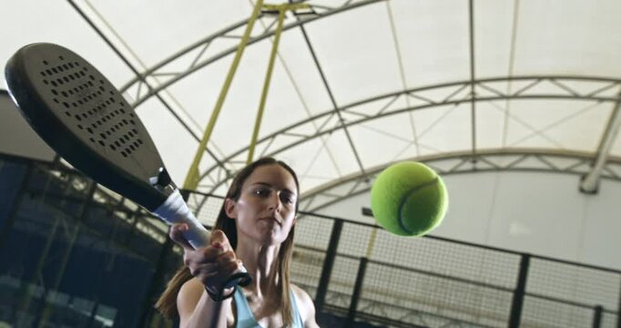 padel, player, woman, athlete, forehand, shot, racket, ball, court, net, action, sport, focus, motion, swing, match, competition, indoor, power, movement, strike, game, energy, agility, precision, spe