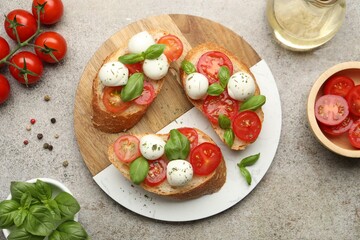Tasty sandwiches with mozzarella cheese balls, tomato and basil on grey table, flat lay