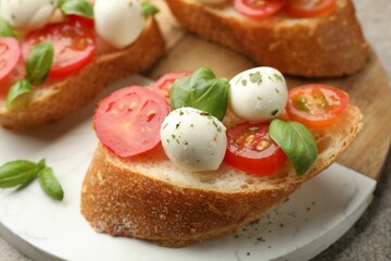Tasty sandwiches with mozzarella cheese balls, tomato and basil on grey table, closeup