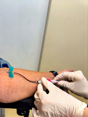 Arm of a patient whose blood is being drawn by a nurse.