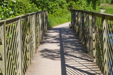 Empty footbridge with metal railing casting shadows on sunny day