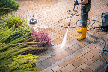 Pressure Washing a Patio in a Residential Backyard, Showcasing Clean Pavers and Vibrant Plants on a Sunny Day
