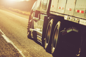 Long Haul Truck Driving on an Open Highway During Sunset With Vibrant Colors in the Sky and a Sense...