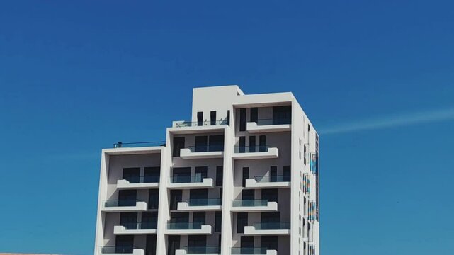 Full View White Color Building With Black Windows And Blue Sky Background. Highrise Tower or Sky Scraper, Building Outdoor Exterior View With Balcony And Terrace PentHouse Apartment G+8 Floor Building