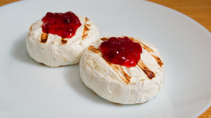 Tasty grilled camembert cheese with cranberries on white plate