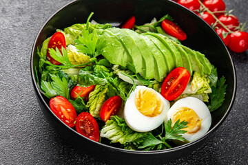 Salad avocado, egg, tomato, green leaf lettuce, vegetable dish fresh gourmet food background on the table rustic food top view copy space keto and paleo diet vegetarian food