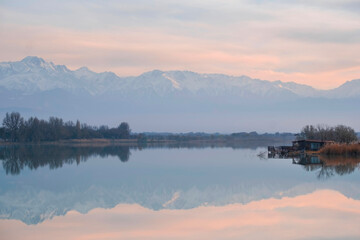 Beautiful autumn landscape when snowy mountains are reflected in the water of a calm lake in calm weather