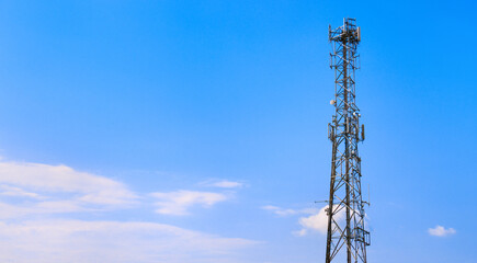 Mobile phone cell tower with telecommunications antennas and microwave dish transmitters. Part of a voice and data cellular communication network to provide signal to devices. On blue sky background.