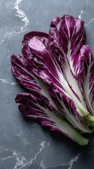 Obraz premium Vibrant radicchio leaves arranged on a gray marble background. The rich purple and white hues create a stunning contrast.
