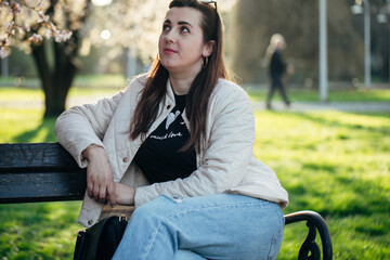 Woman enjoying spring weather in a park while contemplating life moments surrounded by blooming...
