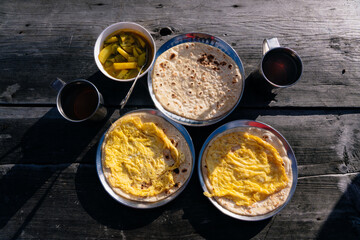 Nepali Trekking Breakfast in the HImalayas Chapati Roti, Black Tea, Potato Curry on a Wooden Table