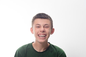 Happy teenage boy smiling broadly, showing his braces against a white background.