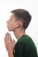 Fototapeta premium A teenage boy in a green T-shirt folded his hands in prayer.