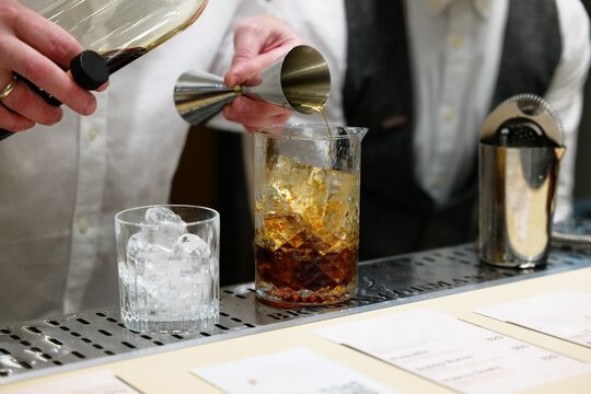 Crafting a signature cocktail with precision at a lively bar