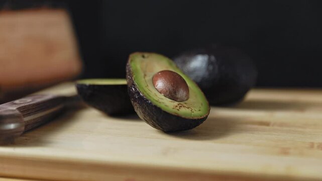 Avocados and knife lie on the wooden cutting board.